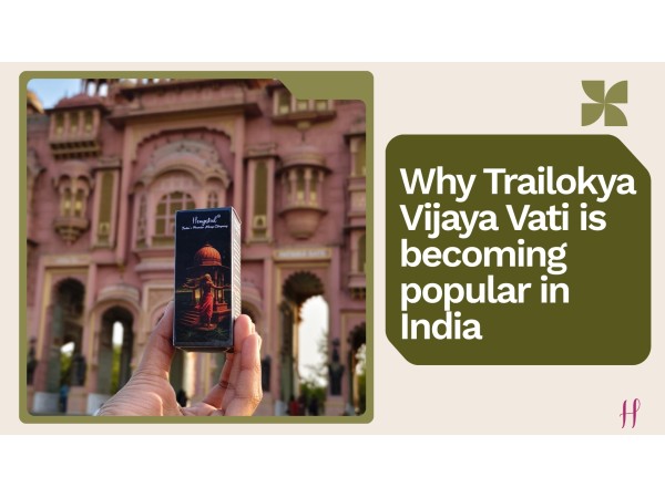 Person holding Trailokya Vijaya Vati in front of a pink architectural building in India